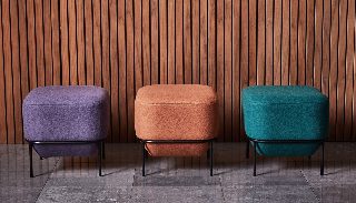 Camira Blazer yün kumaşıyla döşenmiş mor, kiremit ve petrol yeşili üç oturma pufu, ahşap latalı duvar önünde