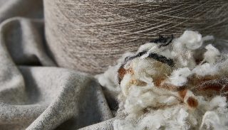 Camira Blazer'ın ham maddesi, doğal ham yün elyafı ve iplik bobini dokunmuş yün kumaş yanında