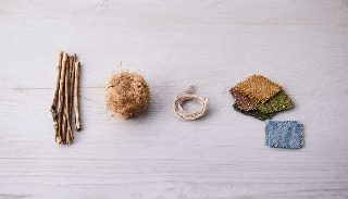Camira Hemp'in ham maddesi: kenevir sapları, ham kenevir lifi topu, eğrilmiş iplik ve bitmiş kumaş örnekleri açık ahşap zeminde