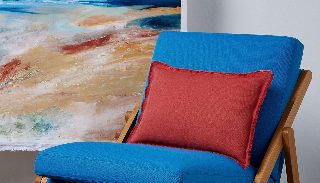 Camira Quest mavi kumaşıyla döşenmiş ahşap katlanır koltuk, kiremit rengi minder ve deniz manzaralı tabloyla