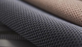 Camira RePlay Zero geri dönüştürülmüş polyester kumaşının gri ve pudra tonlarda iki tonlu hücresel dokusunun yakın çekimi