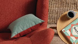 Camira Main Line Flax kiremit rengi kumaşla döşenmiş kanepe, açık yeşil minder ve ahşap yan masayla, jüt halı üzerinde