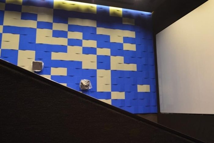 Sinema salonu yan duvarında mavi ve krem dalga formlu 3D akustik panel uygulaması