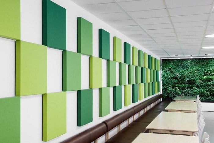 Yemekhane duvarı boyunca yeşil tonlarında kare 3D akustik panel dizilimi ve arkada canlı bitki duvarı