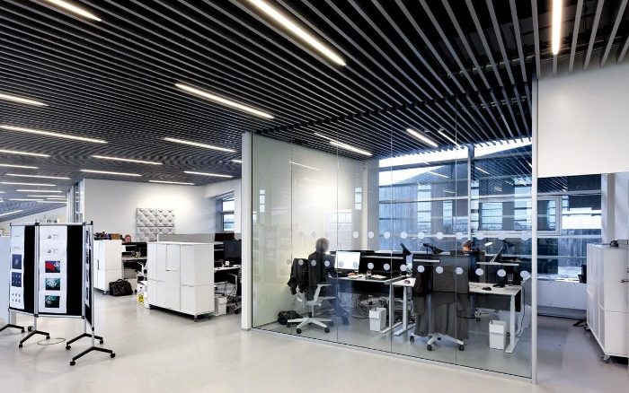 Ofis tavanına paralel sıralı monte edilmiş siyah akustik baffle panel sistemi