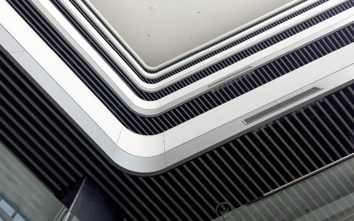 Atrium tavanına eğrisel düzende monte edilmiş beyaz akustik baffle panel şeritleri