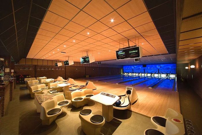 Bowling salonunda ahşap desenli akustik asma tavan uygulaması, mavi ışıklı pistler