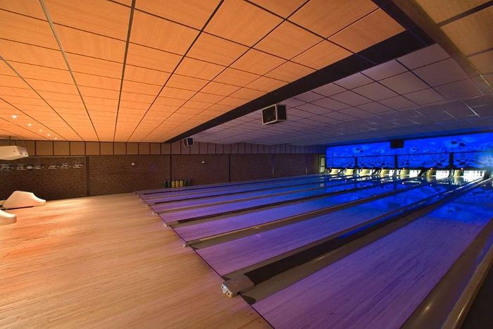 Bowling salonunda geniş açıdan ahşap desenli akustik asma tavan ve ışıklı pistler
