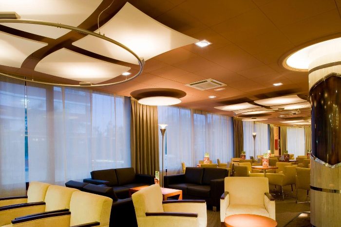 Otel lobisinde metal halkaya asılı yelken biçimli beyaz akustik kanopi panelleri ve daire disk