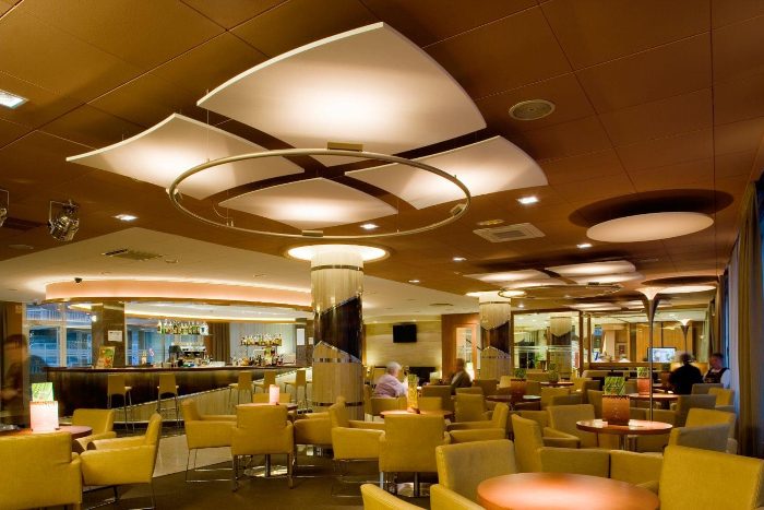 Otel barında yelken biçimli beyaz akustik kanopi panelleri ve daire akustik diskler, bar tezgahı