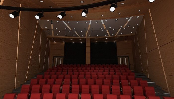Delikli ahşap akustik panellerle kaplı, kırmızı koltuklu tiyatro salonu