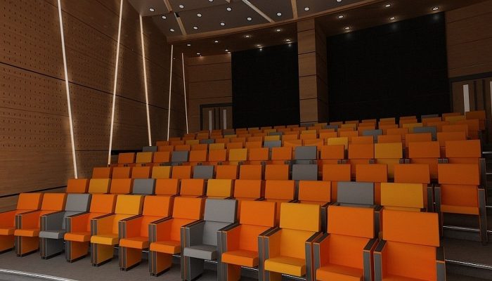Ahşap akustik panelli ve turuncu koltuklu konferans salonu