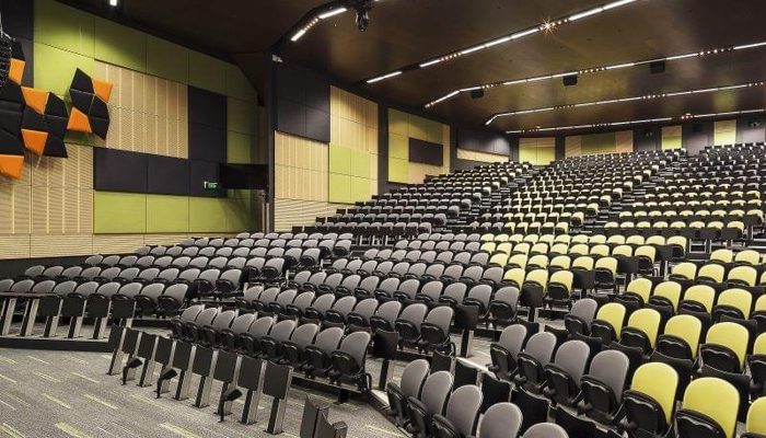Büyük oditoryumda yeşil akustik paneller ve turuncu difüzör uygulaması ile ses düzenlemesi