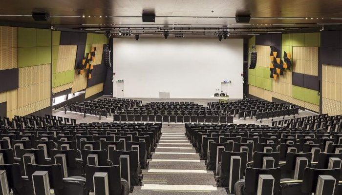 Sinema salonu yan duvarlarında yeşil kumaş kaplı akustik panel uygulaması