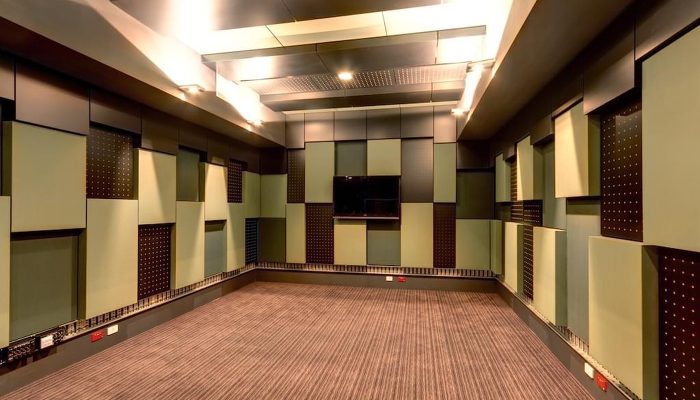 Kayıt stüdyosu duvarlarında yeşil kumaş kaplı akustik panel ve ahşap bant düzeni