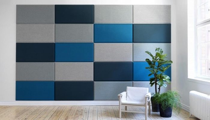 Gri ve mavi tonlarında dikdörtgen akustik kumaş panellerle kaplı geniş oturma alanı duvarı