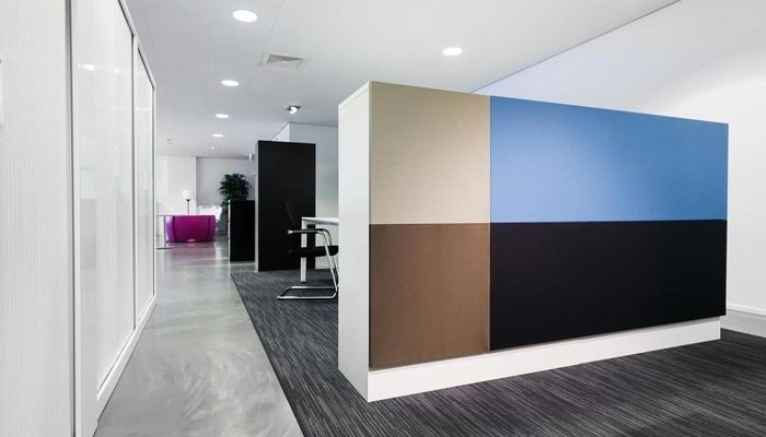 Ofis koridorunda bej, mavi, kahve ve siyah akustik kumaş panelli bölme duvarı