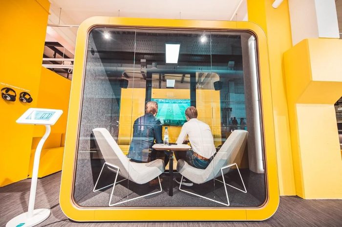 Akustik ofis kabini showroomda sarı model, içeride ekran karşısında iki kişi