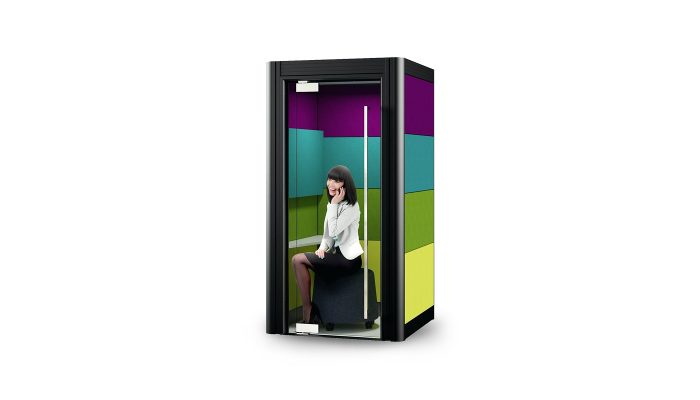 Bağımsız ofis bölümü siyah çerçeveli kabin, mor, turkuaz ve yeşil iç panelleri, pufta telefonla konuşan kadınla