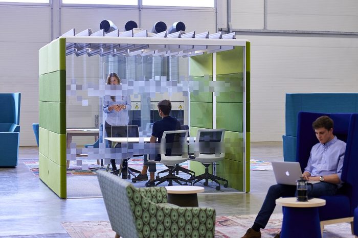 Bağımsız ofis bölümü fıstık yeşili panelli açık tavan lamelli kabin, içinde toplantı yapan iki kişi ve ofis koltukları