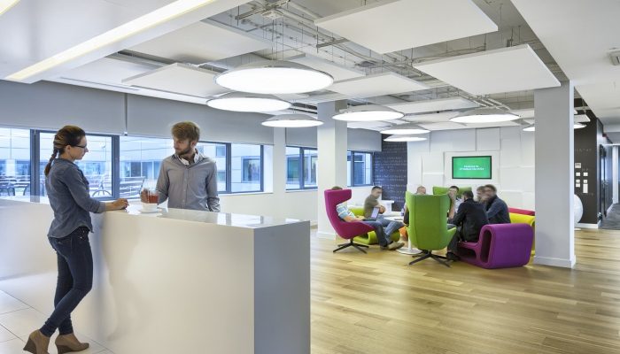 Beyaz tavan panelleriyle düzenlenmiş ofis karşılama ve dinlenme alanı