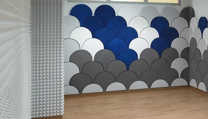 Pul desenli mavi ve gri panellerin piramit kaplamayla buluştuğu duvar