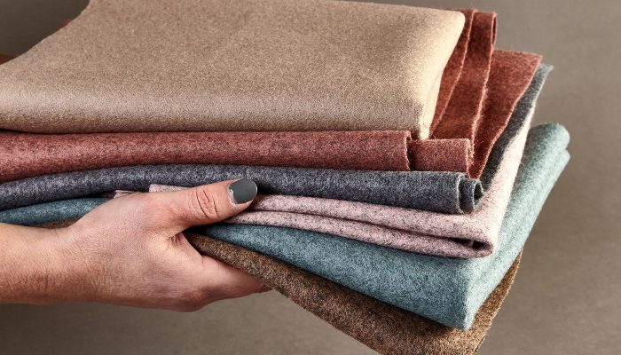 Elde tutulan katlanmış Camira Blazer yün kumaş örnekleri, bej, kiremit, antrasit, pembe ve yeşil doğal tonlar