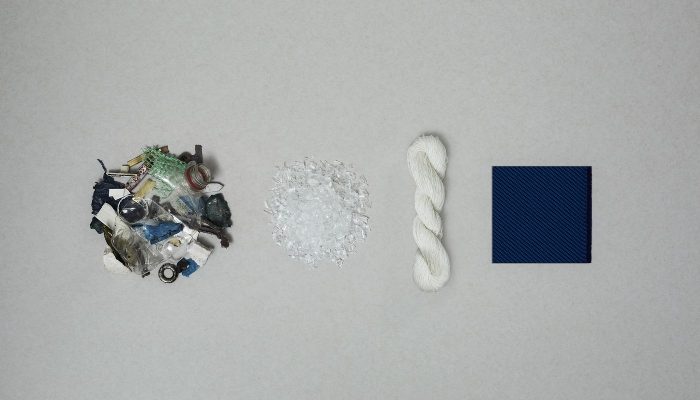Camira Oceanic'in geri dönüşüm süreci: toplanan plastik atık, şeffaf PET pulları, eğrilmiş beyaz iplik ve lacivert bitmiş kumaş