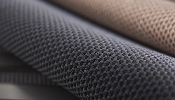 Camira RePlay Zero geri dönüştürülmüş polyester kumaşının gri ve pudra tonlarda iki tonlu hücresel dokusunun yakın çekimi