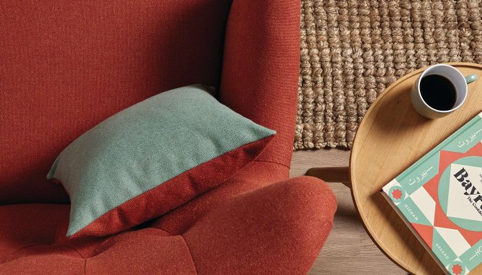 Camira Main Line Flax kiremit rengi kumaşla döşenmiş kanepe, açık yeşil minder ve ahşap yan masayla, jüt halı üzerinde