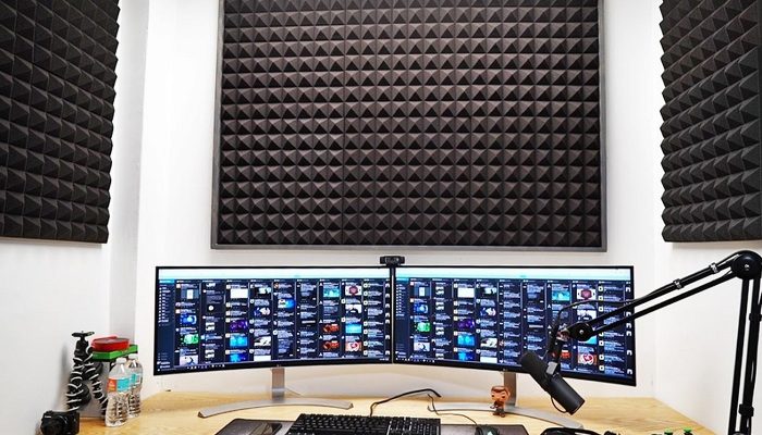 Çift monitörlü yayın masasının arkasındaki piramit köpük panel
