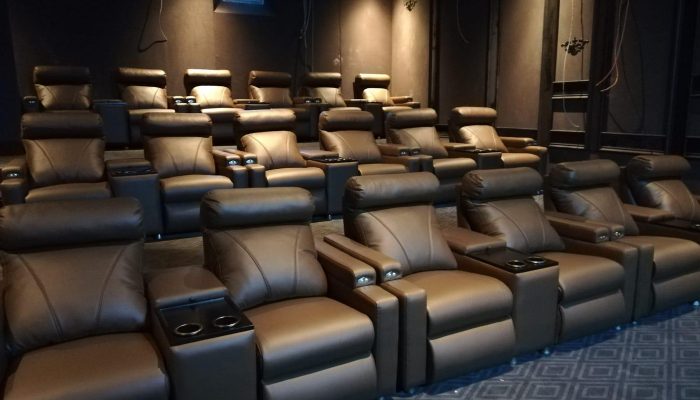 Boş sinema salonunda kademeli sıralar halinde dizilmiş siyah deri koltuklar