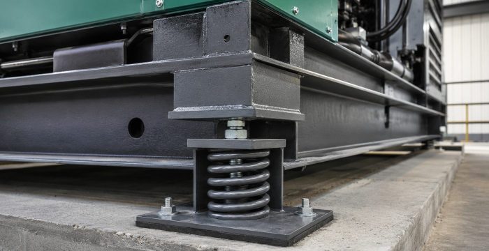 Ara katta jeneratör kaidesi köşesindeki yaylı titreşim izolatörü, çelik yay ve taban plakası detayı