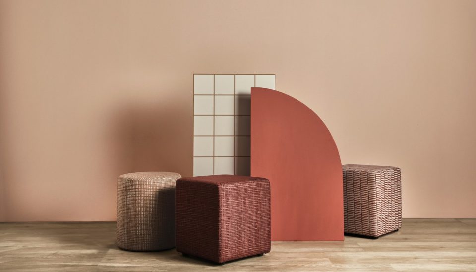 Camira Patternmaker yün kumaşının üç farklı deseniyle döşenmiş yuvarlak, küp ve dikdörtgen tabure, terracotta tonlu dekor önünde